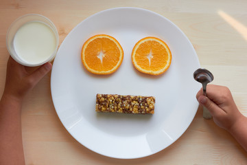 breakfast for a child, oranges, a cereal bar and a glass of milk