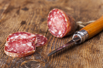 SalamiWurst mit einem Messer auf Holz