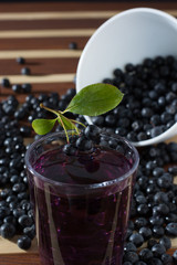 Bowl full of aronia with glass of aronia juice
