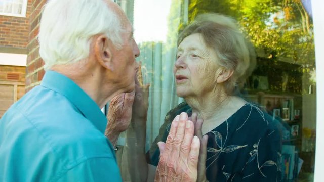 Elderly couple kissing through glass