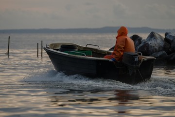 Ein Fischer fährt am frühen Morgen zum Fischfang hinaus. - obrazy, fototapety, plakaty
