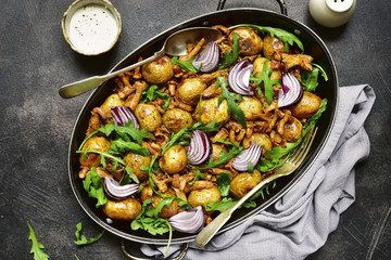 Oven baked new potato with mushrooms,onion and arugula.Top view.