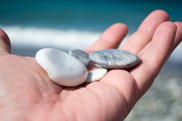 Hand with small stones on the beach