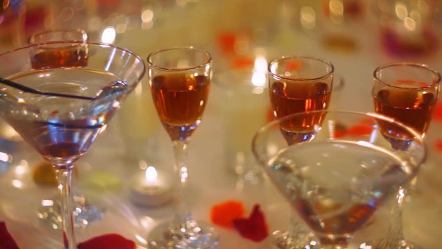 Panning along holiday buffet table with alcohol drinks, decorated with candles and rose petals.