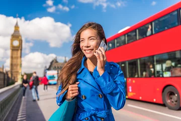 Schilderijen op glas London city businesswoman calling on mobile phone app talking to cellphone on Westminster bridge with red bus and Big Ben, Parliament urban background. Europe destination, England, Great Britain. © Maridav