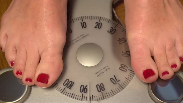 An overweight woman stepping on to a scale