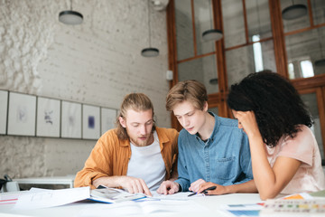 Portrait of young people working in office. Two boys with blond hair and girl with dark curly hair...