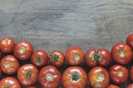 Group of fresh, red tomatoes on old wooden table with copy space. High angle view