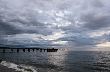 Fototapeta na wymiar storm clouds rolling in over an ocean fishing pier at sunrise