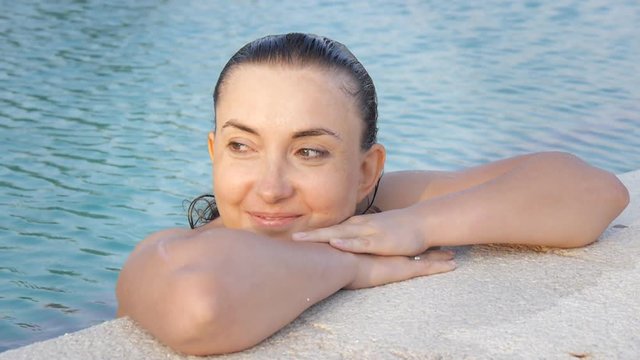 Closeup shot of happy caucasian woman enjoying water on the edge of the pool.