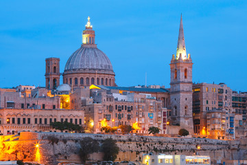 Fototapeta na wymiar Valletta Skyline from Sliema with church of Our Lady of Mount Carmel and St. Paul's Anglican Pro-Cathedral during evening blue hour, Valletta, Capital city of Malta