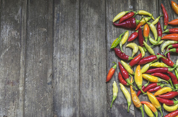 Colorful hot chilli peppers on wooden table with copy space