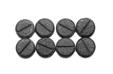 Activated charcoal pills on white background