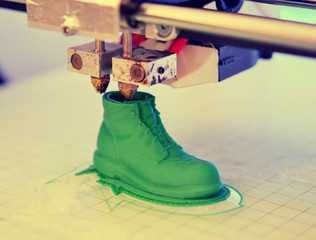 3D printer prints the form of molten plastic green close-up. Automatic three dimensional 3d printer performs plastic modeling in laboratory. Progressive modern additive technology