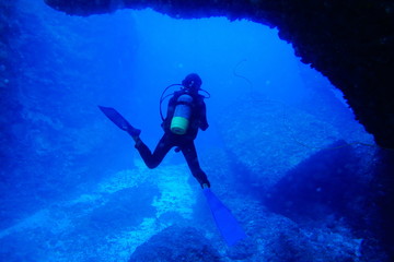 海底の洞窟内で泳ぐダイバー
