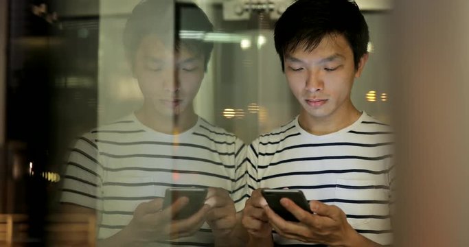 Man using cellphone with window reflection