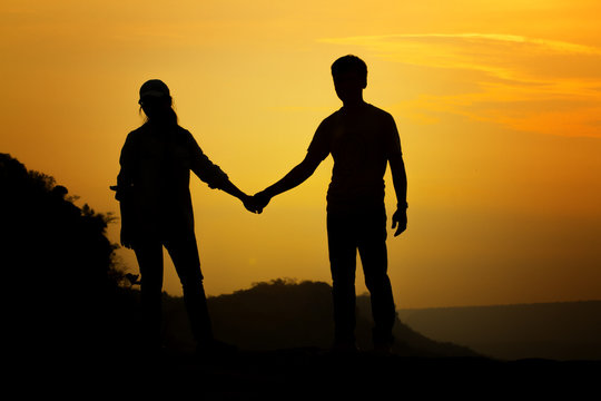 Silhouette couple's holding hand for travelers on sunrise