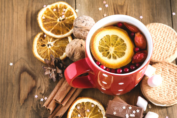 Red cup of hot tea with orange and berries Christmas winter beverage Christmas food concept Wooden background Cinnamone sticks Cookies Toned Above