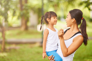 Pleasant loving thai mother holding her little daughter