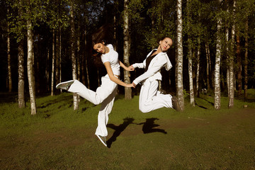 two young girl jump in park