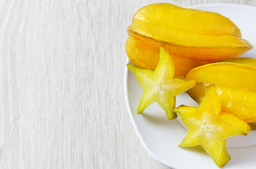 star fruit in a white plate placed on a wooden floor.