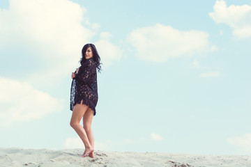 A girl on the beach, rest and relaxes in the sand dunes of the sand. Pretty woman demonstrates a good figure and herself. The concept of a beautiful vacation and beauty of body and soul