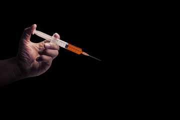 The Doctor's an medical syringe injection in hand, palm or fingers. Liquid drug or narcotic. on black background with copy space. Medical part concept.