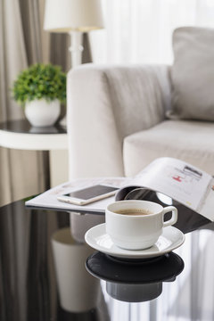 Cup of coffee on a round table with sofa in living room