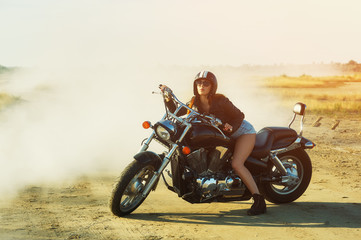 Fototapeta na wymiar Attractive girl on a motorcycle on a dirt road