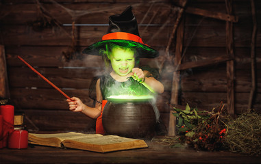 Halloween. little witch child cooking potion in   cauldron with spell book