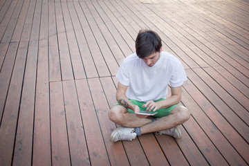 young student using gadget for internet or reading in park