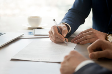 Close up image of businessman hand putting personal signature on contract document in presence of business partner. Starting successful partnership with entrepreneur or companie, making good deal - obrazy, fototapety, plakaty