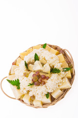 Set of cheeses with grapes in a round basket on a white background. Isolated.