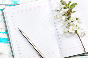 Naklejka premium Notepad, pen and branch with cherry blossom on the table.