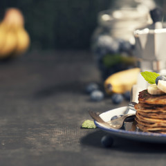 Homemade pancakes with fresh bananas, blueberries and honey