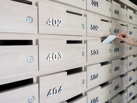 Close-up of person's hand . hand removing a letter from mailbox in the entrance hall of an apartment building