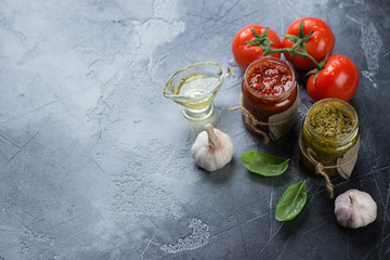 Red and green pesto sauces on a grey stone background, horizontal shot with copyspace