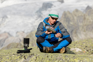 Alpinist makes a break in the mountains and pours a tea