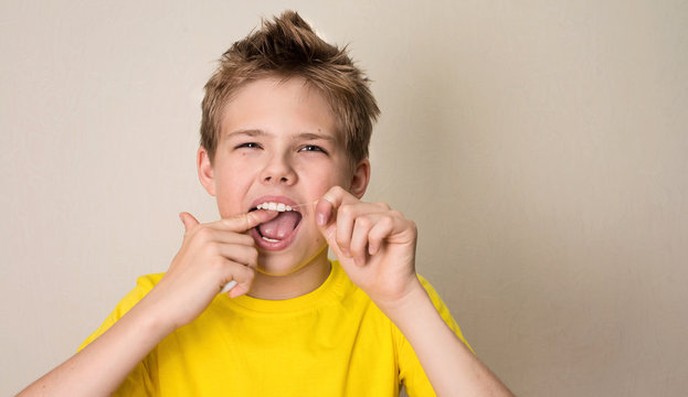 Boy flossing teeth. Close-up portrait of teen boy with dental floss isolated.