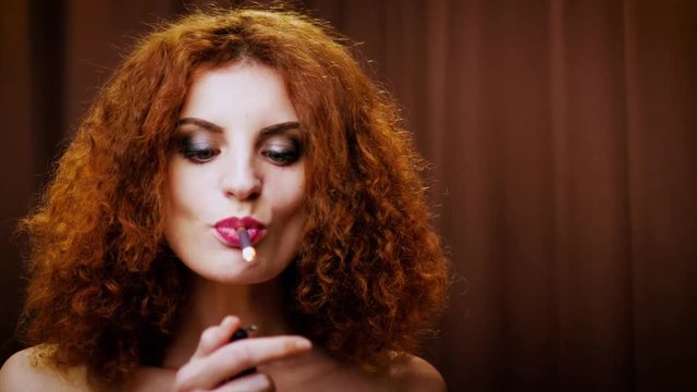Wild and free girl  is definitely enjoying a strong black cigarette. A gorgeous redhead with piercing blue eyes demonstrates that her smoking habit is a huge deal for her.