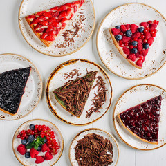 Fruit and berry piece of  tart  assorted top view background. Beautiful delicious tarts, bright, colorful pastry cakes sweets with fresh raspberries, chocolate, strawberry.