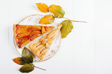 Two piece of apple and pear pie decorated with branches with leaves on wooden background. Autumn...