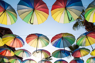 Colorful umbrellas background.Multi-colored umbrellas in the sky floating above the street against palms trees. Umbrella Sky Project in Marmaris, Turkey