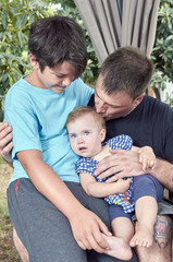 Father with his son and baby. Father is kissing his girl baby.