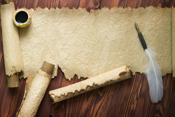 white feather and ancient scroll on brown plank