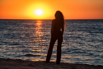 Fototapeta premium Silhouette young woman on the beach at sunset