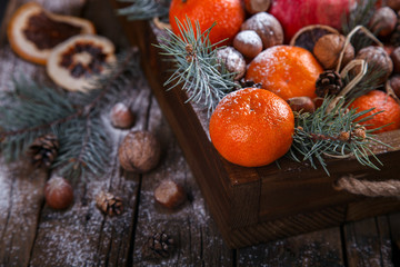 Christmas New Year  card. Tangerines,Nuts,Pomegranate,Citrus,Tree Branches  in a wooden box.Festive Background.Vintage style.selective focus.