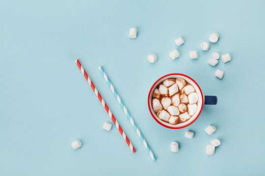 Mug of hot cocoa or chocolate and straw on turquoise table top view. Flat lay.