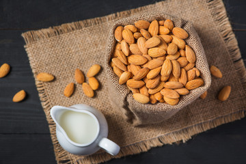 Almond milk in glass with almonds on  black wooden table