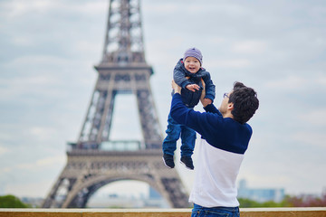 Naklejka premium Ojciec wyrzucający swojego małego synka w powietrze w pobliżu wieży Eiffla